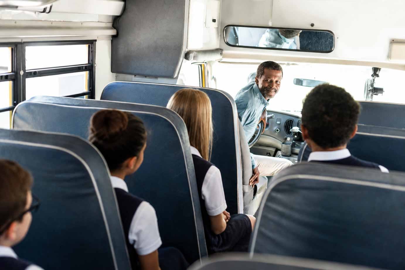 A Beremi driver turning to greet school learners in uniform on the bus